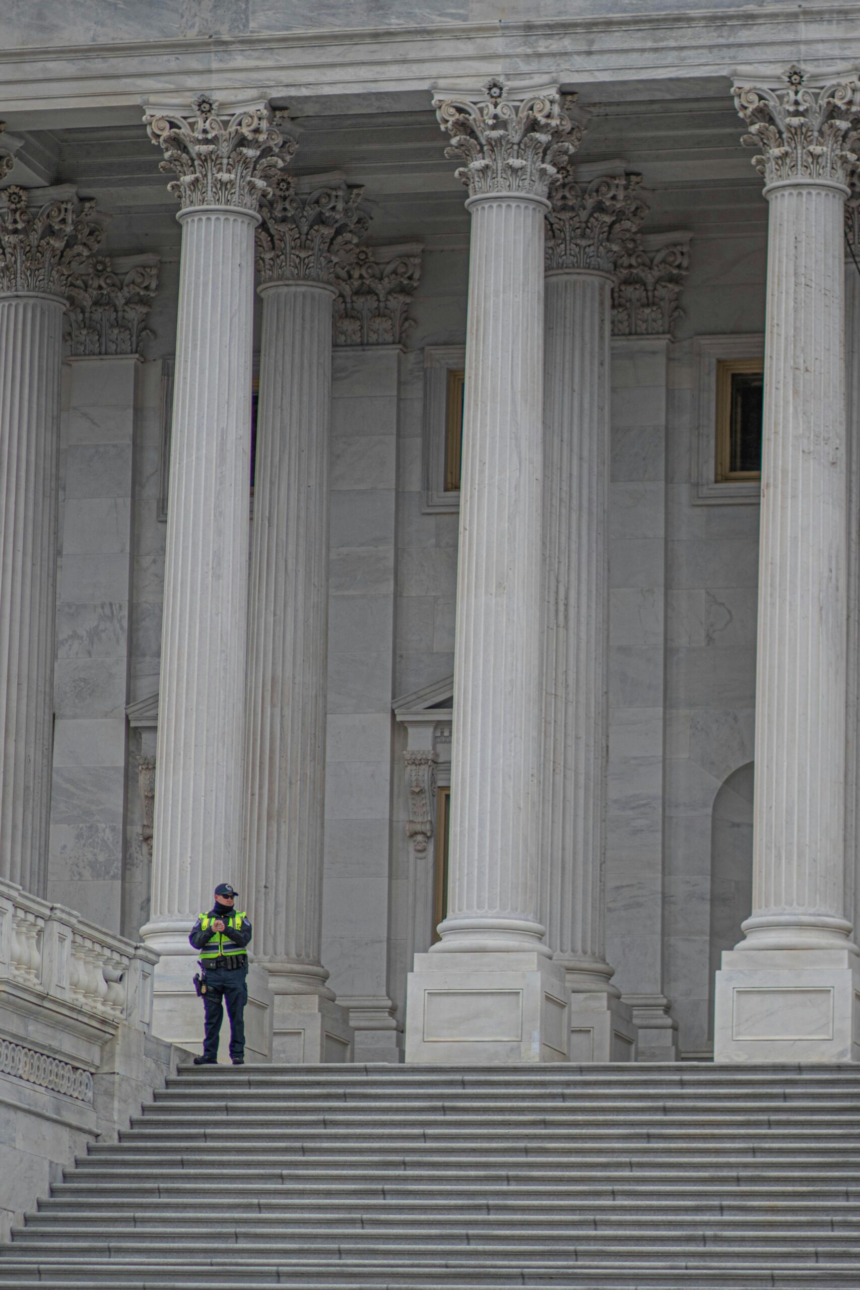 Neoclassical architecture of Capitol Building in Washington, DC, with security presence.