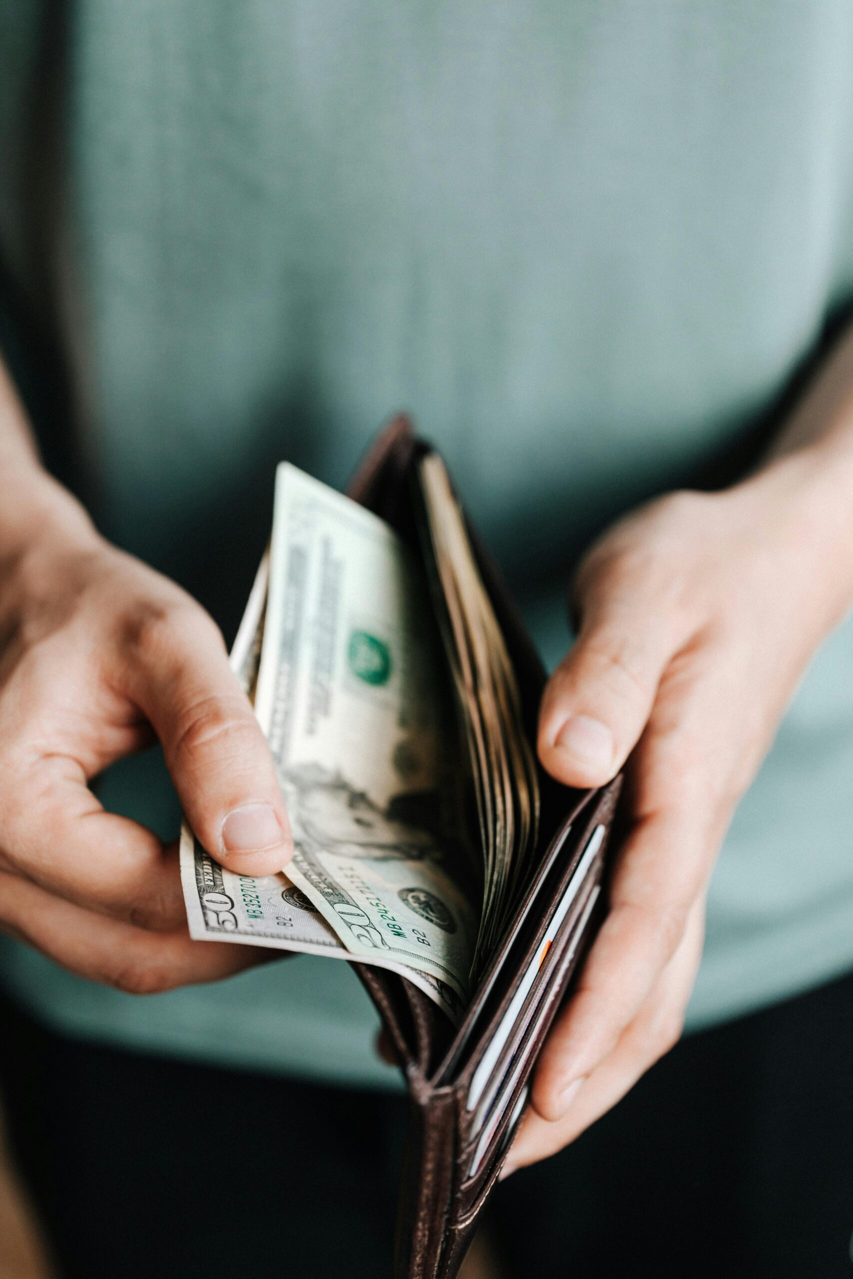 Close-up of hands holding a wallet with cash, depicting financial management.